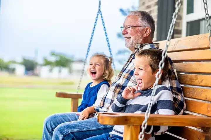 Grandfather with grandchildren sitting on porch swing in Lexington KY